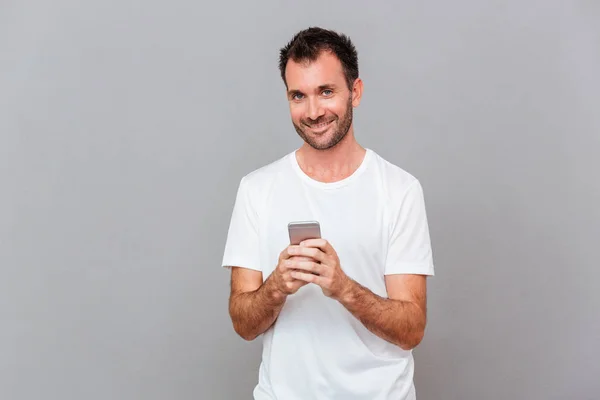 Sujetador feliz sosteniendo teléfono inteligente y mirando a la cámara — Foto de Stock