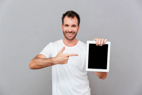 Красивый мужчина указывает пальцем на пустой экран планшетного компьютера — стоковое фото