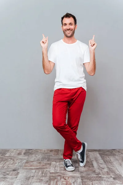 Portrait of a smiling casual man pointing two fingers up — Stock Photo, Image