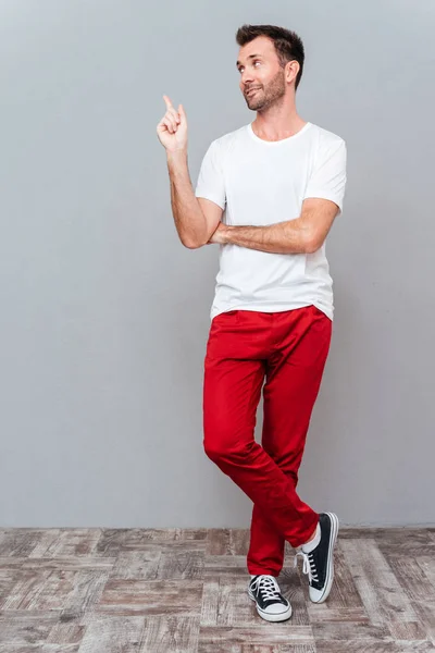 Longitud completa de un hombre casual sonriente señalando con el dedo — Foto de Stock