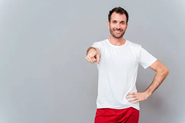 Smiling young man pointing finger at camera — Stock Photo, Image