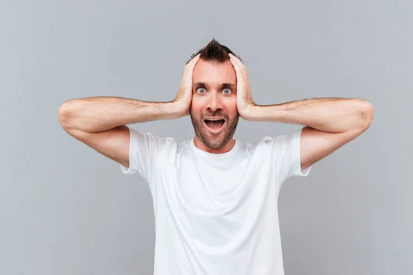 Stressed young man covers ears by hands and shouting — Stock Photo, Image