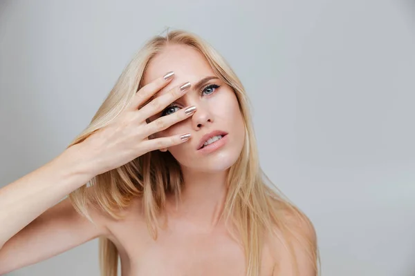 Mujer rubia sonriente mirando a la cámara a través de los dedos — Foto de Stock