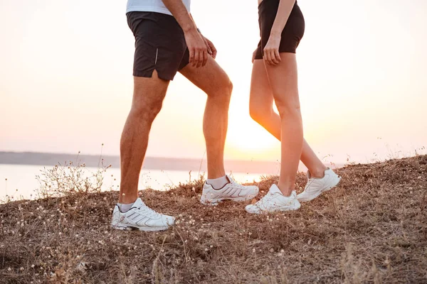 Jeune couple de fitness debout pendant le coucher du soleil sur la colline — Photo