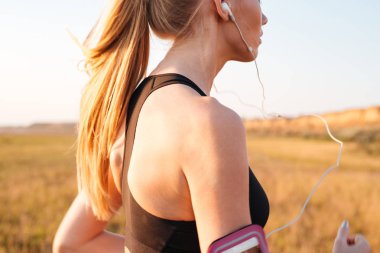 Earphones ile çalışan bir sarışın spor kadın Resim kırpılmış