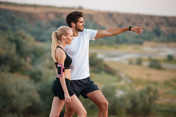 Joven hermosa pareja de fitness de pie en una colina — Foto de Stock
