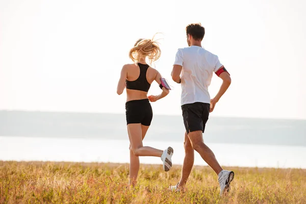 Vista posteriore di giovane uomo e donna che fanno jogging — Foto Stock