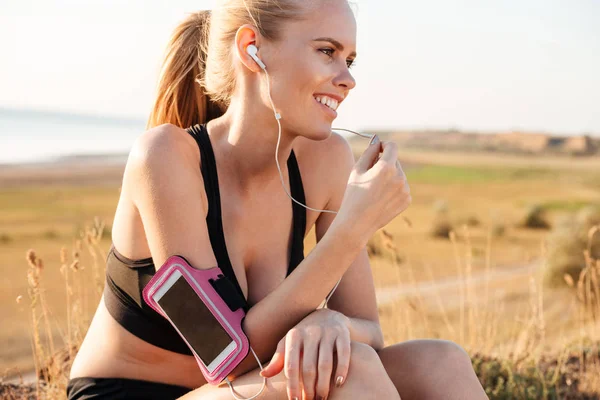 Kvinna löpare lyssnar på musik med mobiltelefon i armband — Stockfoto