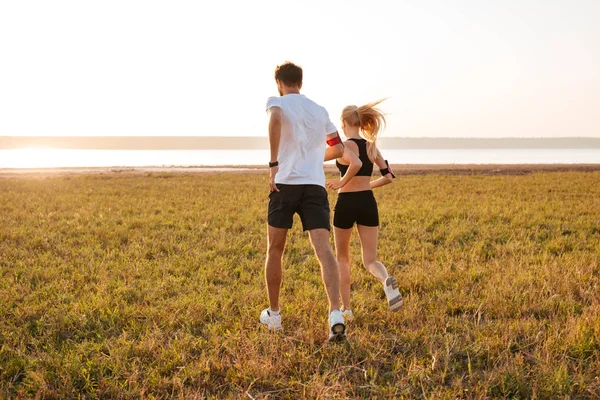 Vista posterior de un joven fitness hombre y mujer haciendo footing — Foto de Stock