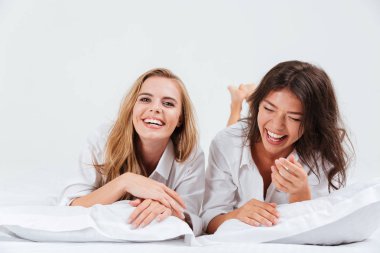 İki kadın birlikte yatan gülüyor ile beyaz yaprak yatak