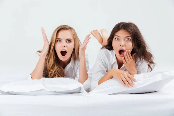 Vrouwen liggend op bed met kussens en camera te kijken — Stockfoto