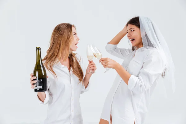 Due amiche felici che festeggiano il fidanzamento con velo e bottiglia di champagne — Foto Stock