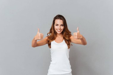 Başparmak gösterilmesini rahat gülümseyen genç bir kadın portresi
