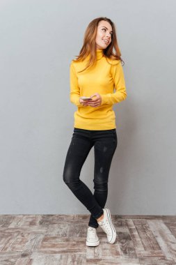 Cep telefonu tutarak ve uzağa arıyorsunuz gülümseyen genç kadın