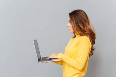 Yan görünümü dizüstü bilgisayarda yazarak neşeli bir kadın portresi