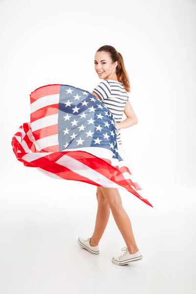 Happy young woman walking and holding usa flag
