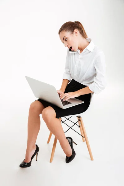 Empresária ocupada usando laptop e falando ao telefone — Fotografia de Stock