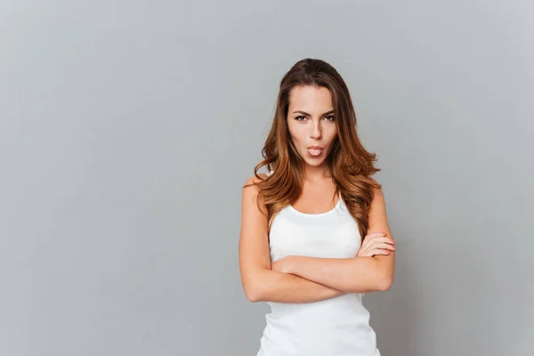 Retrato de una joven juguetona mostrando la lengua con los brazos cruzados — Foto de Stock