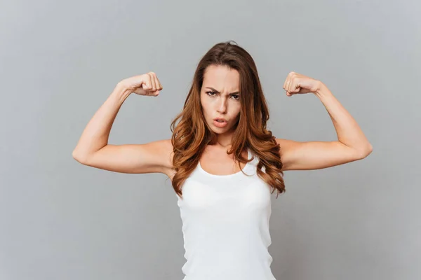 Portrait of a casual young woman showing her muscles — Stock Photo, Image