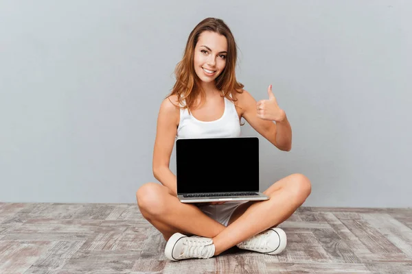 Mujer sentada en el suelo con portátil y mostrando los pulgares hacia arriba —  Fotos de Stock