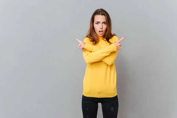 Retrato de una mujer en suéter amarillo apuntando con los dedos hacia otro lado —  Fotos de Stock