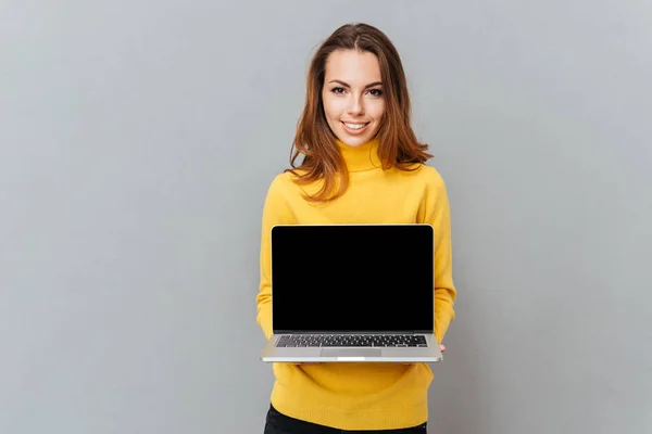 Sonriente joven mujer mostrando la pantalla del ordenador portátil en blanco — Foto de Stock