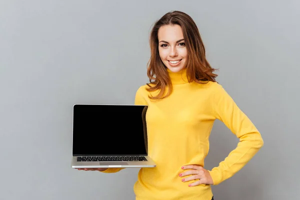 Mujer linda feliz mostrando pantalla de ordenador portátil en blanco — Foto de Stock