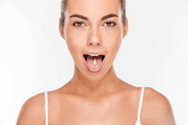 Portrait d'une jolie fille avec capsule vitaminée sur la langue — Photo