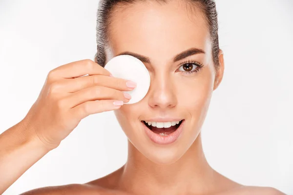 Mujer sonriente sosteniendo almohadilla redonda de algodón blanco en su ojo —  Fotos de Stock