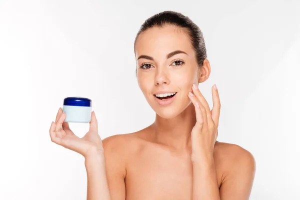 Young woman putting cream on her face — Stock Photo, Image