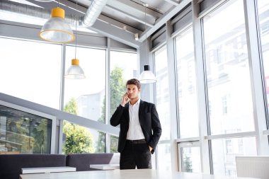 Ayakta ve kafede cep telefonuyla konuşan işadamı