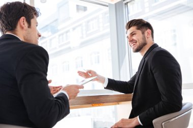 İki neşeli Genç İşadamları tablet iş toplantı üzerinde kullanma