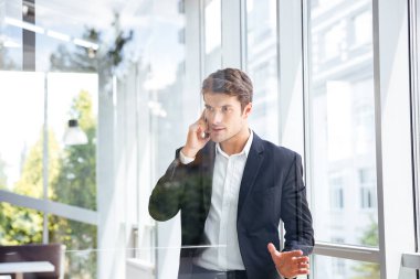 Ayakta ve cep telefonu Office konuşurken işadamı