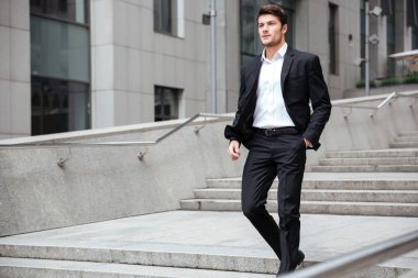 Takım elbiseli bir işadamı sokakta yürüyor.