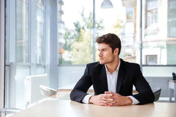 Jeune homme d'affaires pensif assis et pensant dans le bureau — Photo