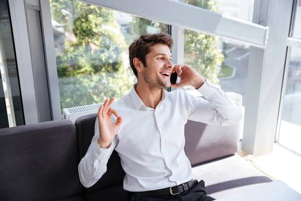 Hombre de negocios alegre mostrando buen gesto y hablando por teléfono celular — Foto de Stock