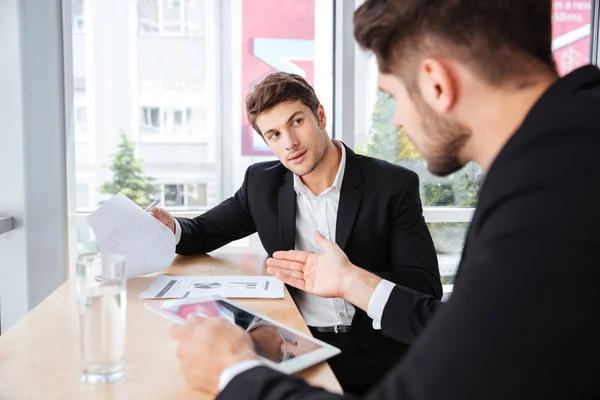 Dos jóvenes hombres de negocios discutiendo el plan de negocios y el uso de tabletas —  Fotos de Stock