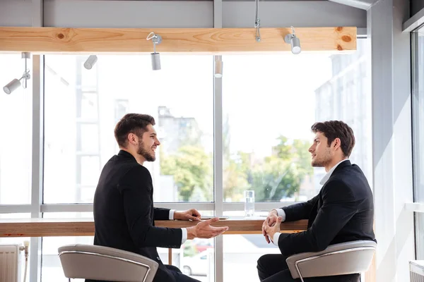 Twee vrolijke jonge ondernemers hebben zakelijke bijeenkomst — Stockfoto