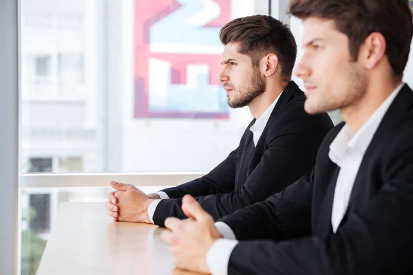 Двоє концентрованих молодих бізнесменів сидять на посаді — стокове фото