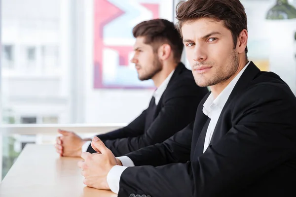 Zwei ernsthafte junge Geschäftsleute sitzen im Büro — Stockfoto