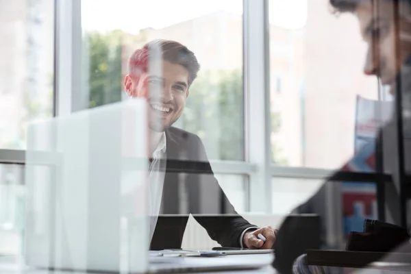 Two cheerful young businessmen with laptop on business meeting — Stock Photo, Image