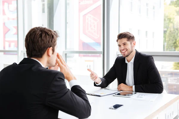 Two happy young businessmen sitting and talking on business meeting — Stock Photo, Image