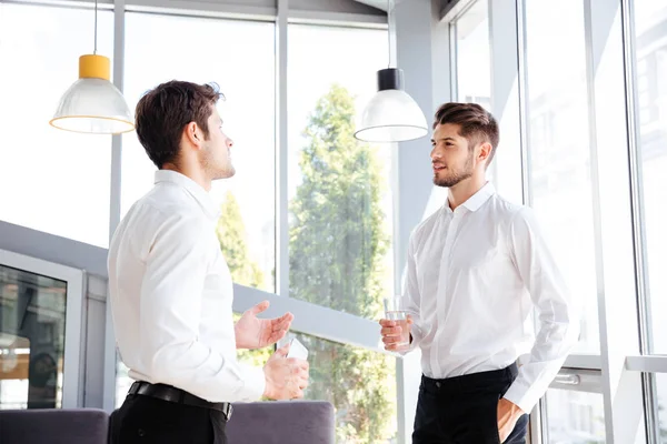 Two businessmen talking and drinking water in office — Stock Photo, Image