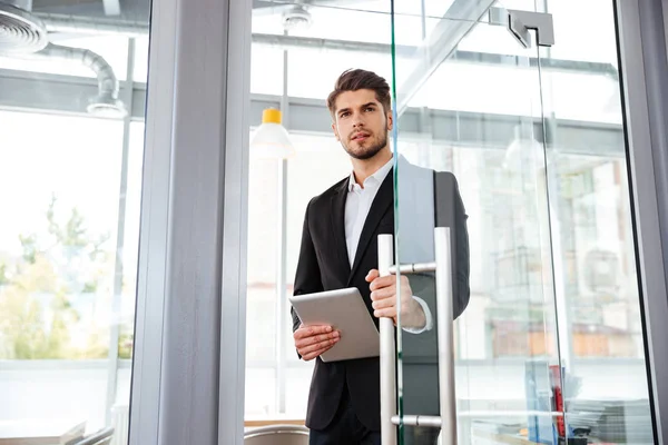 Businesman s tabletem vstupu do dveří v úřadu — Stock fotografie