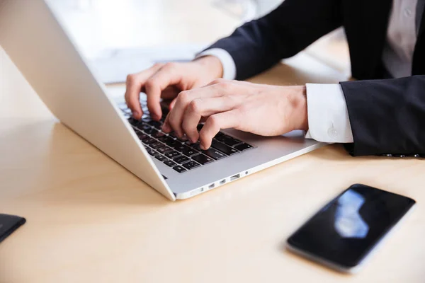 Hands of businessman using laptop and blank screen cell phone — Stock Photo, Image