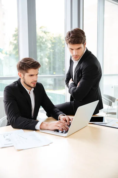 Два бизнесмена используют ноутбук в офисе вместе — стоковое фото