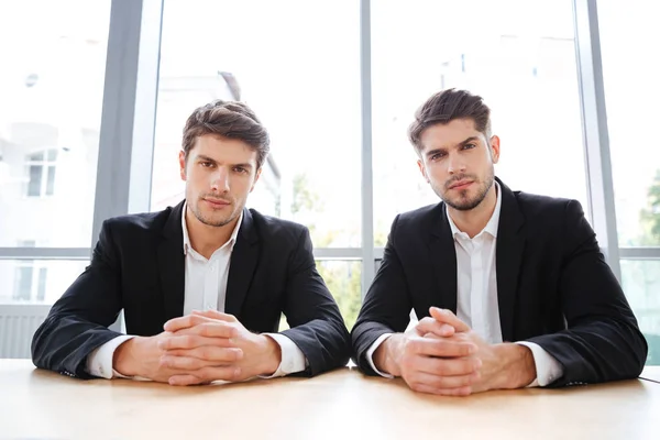 Δύο σοβαρές νέους επιχειρηματίες που κάθεται στο γραφείο — Φωτογραφία Αρχείου