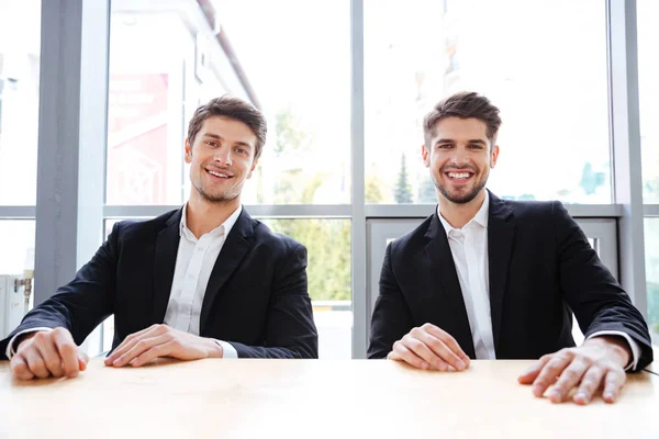Δύο χαρούμενα επιχειρηματιών που κάθεται στο τραπέζι στο γραφείο — Φωτογραφία Αρχείου