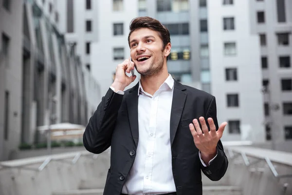 市では、携帯電話で話している幸せな青年実業家 — ストック写真