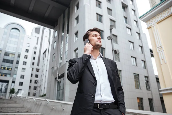 Allvarlig ung affärsman talar i mobiltelefon nära Businesscenter — Stockfoto